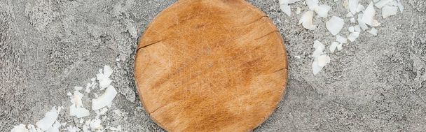 top view of coconut shavings near wooden board on grey textured background, panoramic shot - Fotó, kép