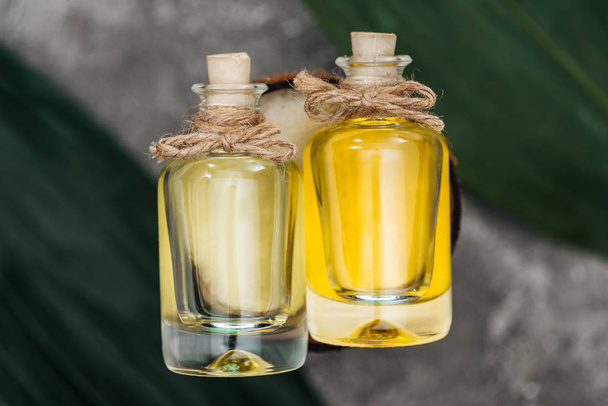 top view of bottles with coconut oil and corks on coconut half  - Φωτογραφία, εικόνα