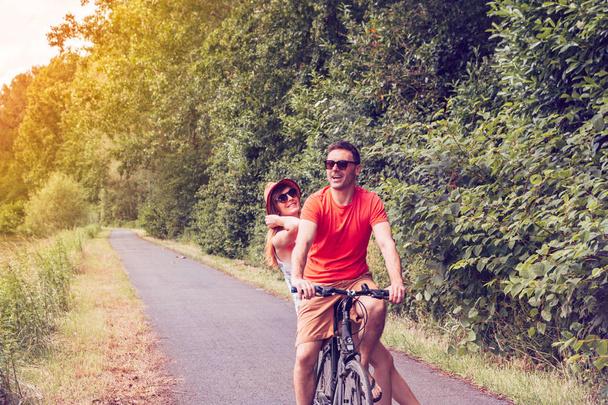 美しい自然の中で夏の晴れた日にサイクリング幸せなカップル - 健康的なライフスタイル、レジャー活動、休日、関係の概念 - 写真・画像