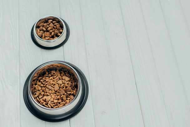 metal bowls with pet food on white wooden surface - Photo, Image