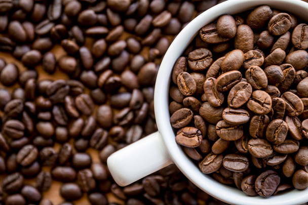 біла чашка кави, повна кавових зерен, насіння на поверхні столу
  - Фото, зображення