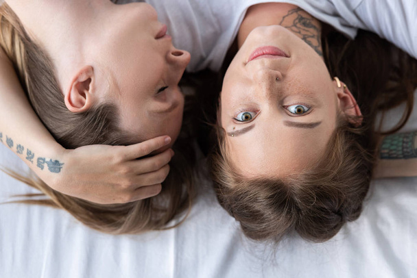 Top widok z dwóch lesbijek obejmując leżąc na łóżku - Zdjęcie, obraz