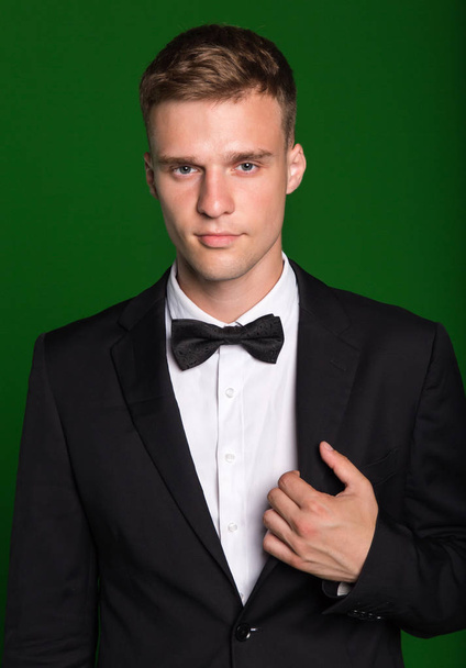 Portrait of a young man in a suit and bow tie isolated on a green background. - Foto, immagini