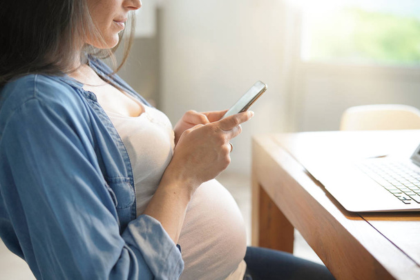 Pregnant woman working from home with laptop  - Foto, afbeelding
