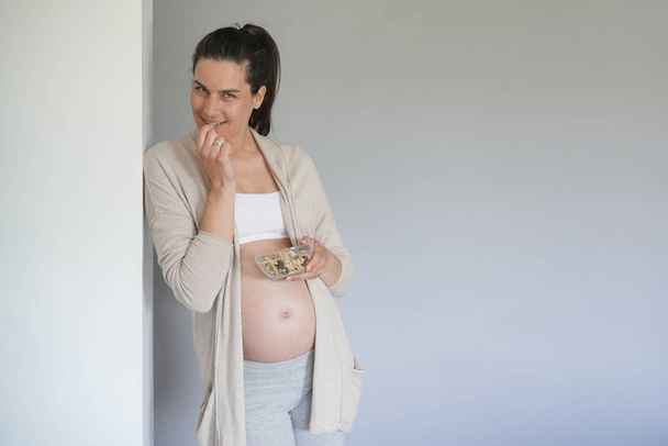 Pregnant woman eating cereals, isolated - Foto, afbeelding