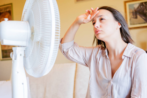Chica delante de ventilador eléctrico tratando de refrescar
 - Foto, Imagen