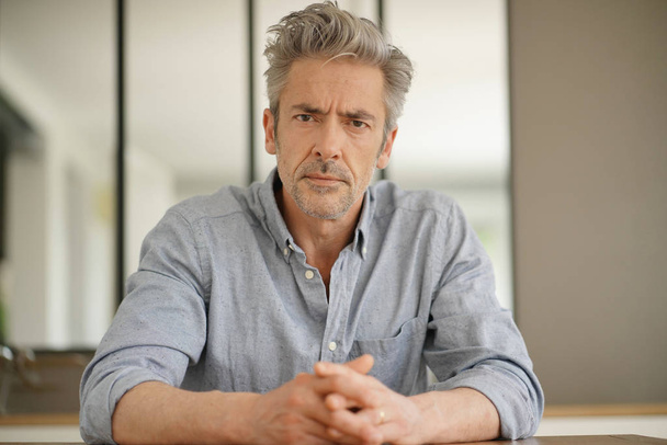 Portrait of handsome mature man looking at camera in contemporary home - Foto, imagen