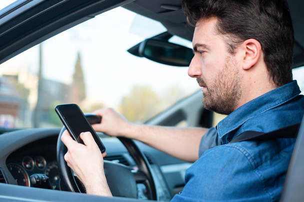 Αρσενικό σε αυτοκίνητο χρησιμοποιεί κινητό τηλέφωνο στο τιμόνι - Φωτογραφία, εικόνα