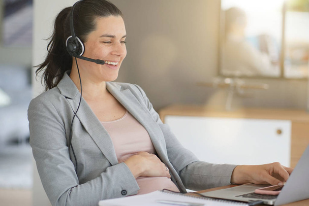 Pregnant woman working in telemarketing department - Zdjęcie, obraz