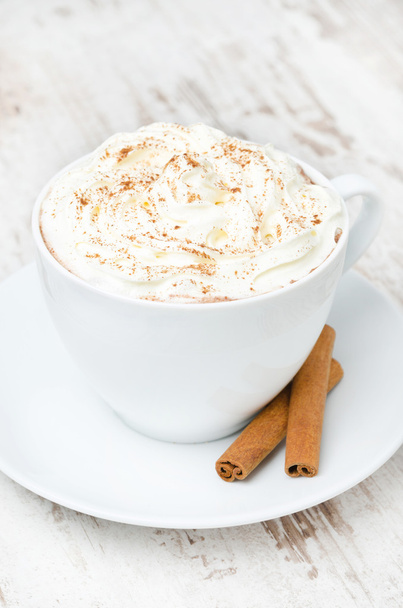 cup of cocoa with cinnamon and whipped cream on white table - Fotó, kép