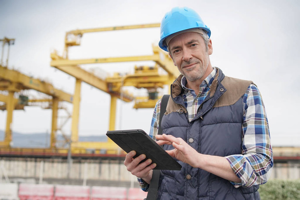 Volwassen bouwvakker inspecterende werk zicht met Tablet - Foto, afbeelding