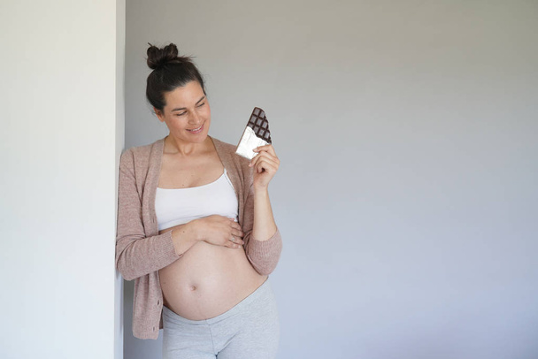 Pregnant woman craving for chocolate bar, isolated - Foto, afbeelding