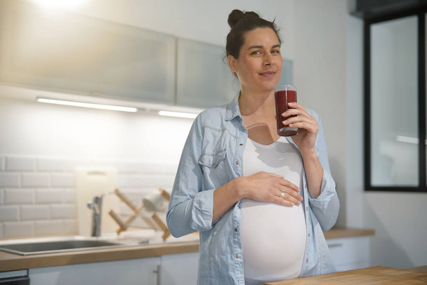 Pregnant woman at home drinking smoothie - Фото, зображення