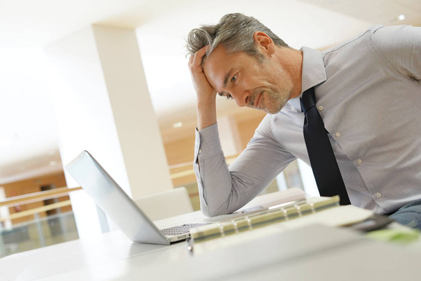 Mature businessman looking stressed at computer - Foto, afbeelding