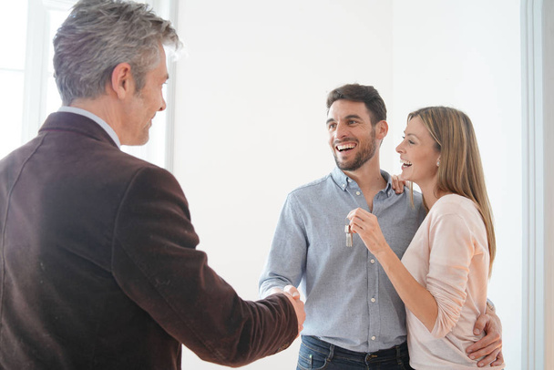 Estate agent handing over keys to happy new home owners - Fotoğraf, Görsel