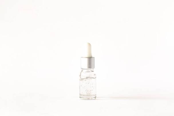 Cosmetic or medical bottle with pipette on white background. Oily drop falls from cosmetic pipette.  - 写真・画像