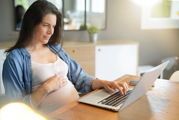 Pregnant woman working from home with laptop  - Fotó, kép