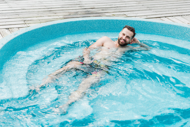 happy bearded man in swimming pool looking at camera   - Фото, изображение