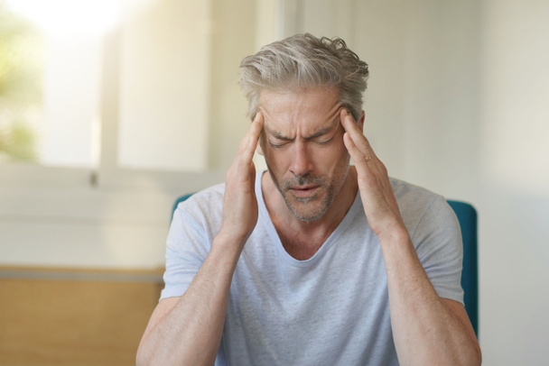 Hombre maduro con dolor de cabeza en casa
 - Foto, imagen