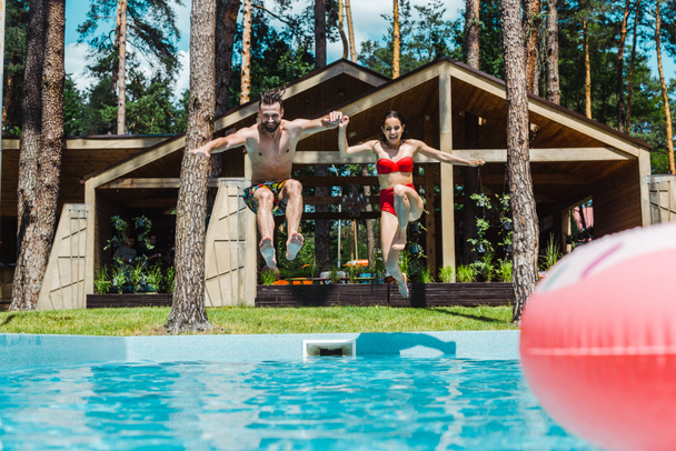 selective focus of cheerful woman and man jumping in water  - Photo, Image