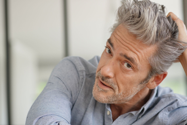 Portrait of handsome mature man looking at camera in contemporary home - Photo, Image