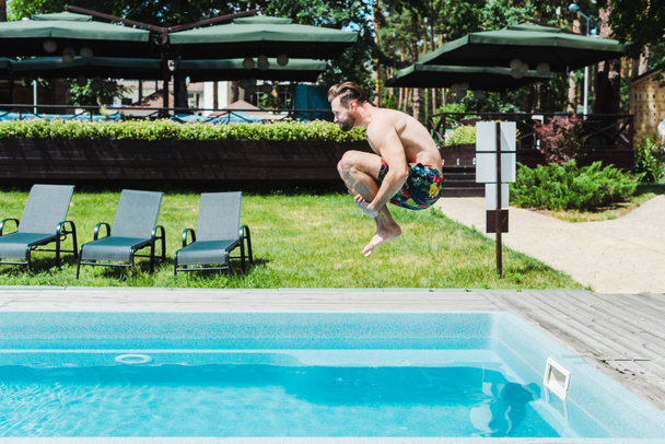 вид сбоку босоногого мужчины с прыжками на батуте в бассейне
  - Фото, изображение