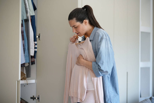 Pregnant woman choosing clothes in closet - Foto, imagen