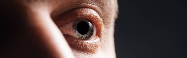 close up view of human eye looking away isolated on black, panoramic shot - Valokuva, kuva
