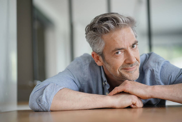 Portrait of handsome mature man looking at camera in contemporary home - Photo, image