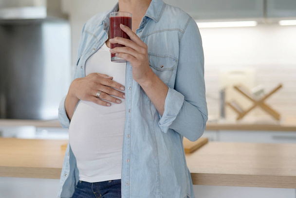 Pregnant woman at home drinking smoothie - Fotó, kép