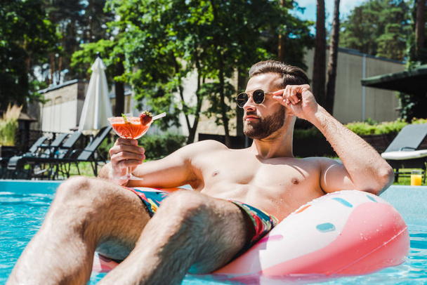 valikoiva painopiste mies koskettaa aurinkolasit ja tilalla cocktail lasi
  - Valokuva, kuva