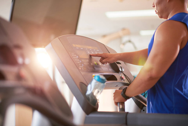 Sporty man choosing program on treadmill before running - 写真・画像