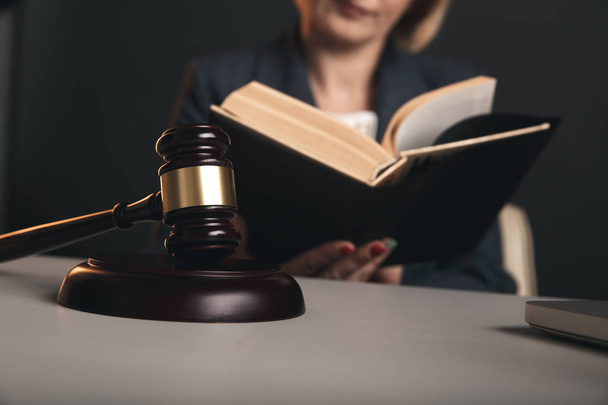 İşyerinde hukuki kitaplarla çalışan kadın avukat. Toklak ve terazi masada. - Fotoğraf, Görsel
