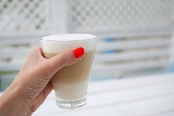 Zonneterras café met een latte in een glas op de tafel. - Foto, afbeelding