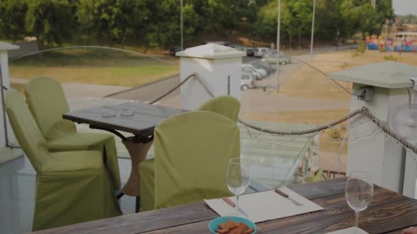 Een mooie vrouw zit aan een tafel in een restaurant op het open terras en zet de telefoon op de tafel. - Video