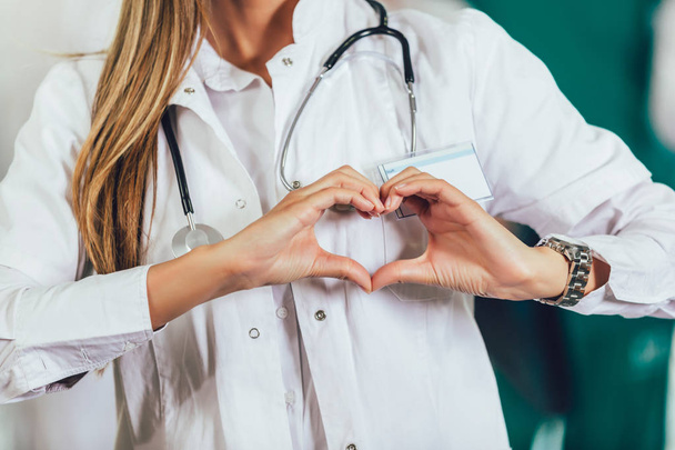 Retrato de una doctora mostrando un gesto cardíaco con las manos
 - Foto, Imagen