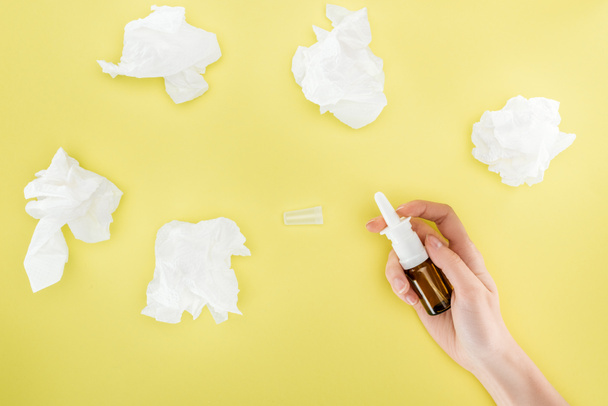 cropped view of woman holding nasal spray near napkins isolated on yellow - Photo, Image