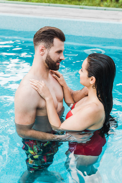 брюнетка жінка обіймає красивого бородатого чоловіка в басейні
  - Фото, зображення