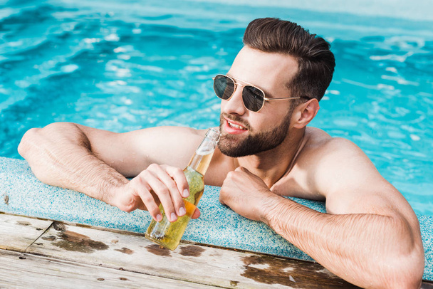 happy bearded man in sunglasses holding bottle with beer  - Foto, Imagen