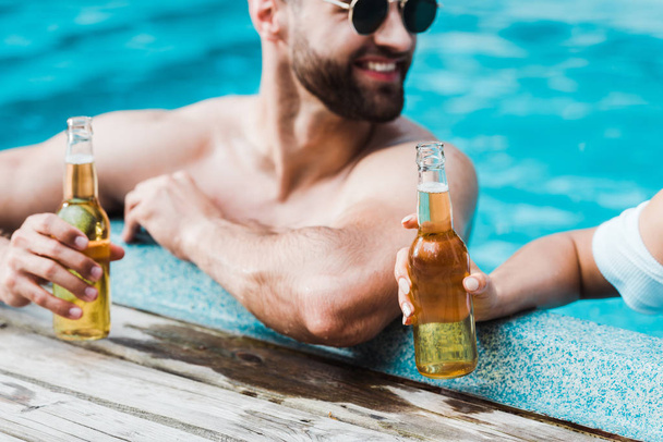 selective focus of happy man holding bottle with beer near woman  - Photo, Image