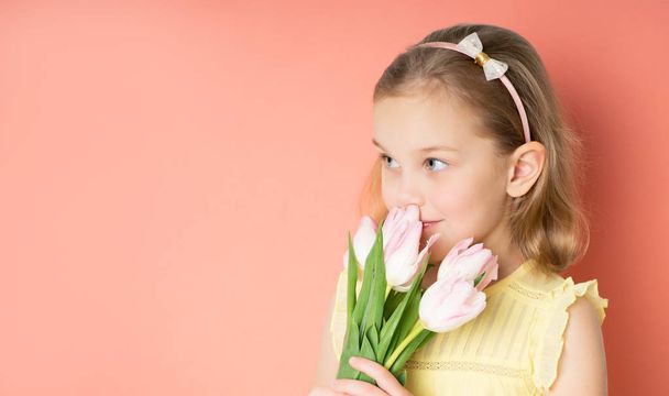 Портрет красивої молодої дівчини в сукні, що тримає великий букет тюльпанів, ізольованих на рожевому фоні
 - Фото, зображення