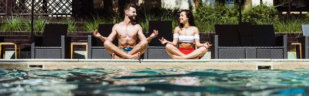 panoramic shot of happy woman and handsome man meditating near swimming pool   - Foto, Bild