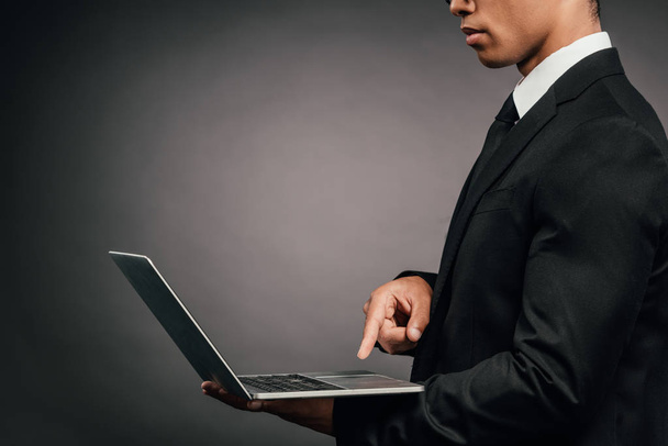 partial view of african american businessman using laptop on dark background - Photo, Image
