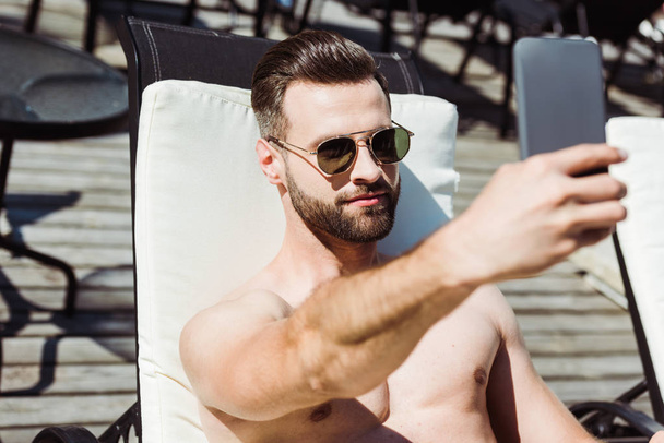 επιλεκτική εστίαση του όμορφου άντρα με γένια παίρνοντας selfie στο smartphone  - Φωτογραφία, εικόνα