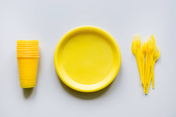 Single use picnic yellow utensils, plates, cups, forks on grey. Top view. Space for text. - Foto, immagini