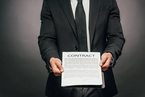 cropped view of african american businessman showing contract on dark background - Foto, immagini