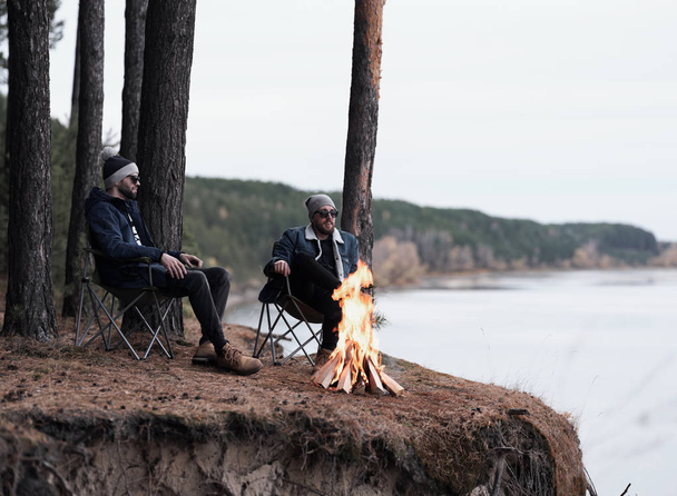 Male friends relaxing by campfire  - Foto, imagen