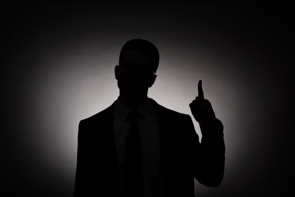 silueta negra del hombre de negocios mostrando signo de idea con luz de fondo
 - Foto, Imagen