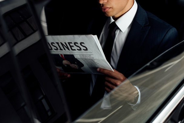 rajattu näkymä afrikkalainen amerikkalainen liikemies lukeminen liiketoiminnan sanomalehti autossa
 - Valokuva, kuva