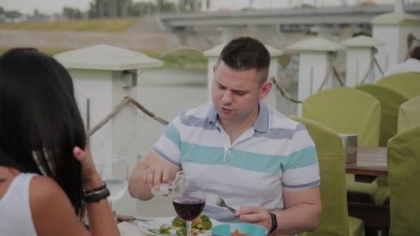 Young man and woman having lunch in a restaurant on the outdoor terrace. - Filmati, video